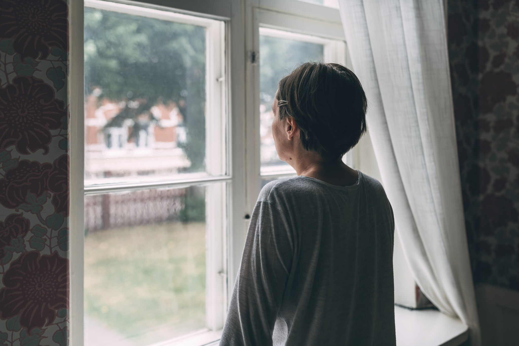 Frau schaut traurig aus dem Fenster
