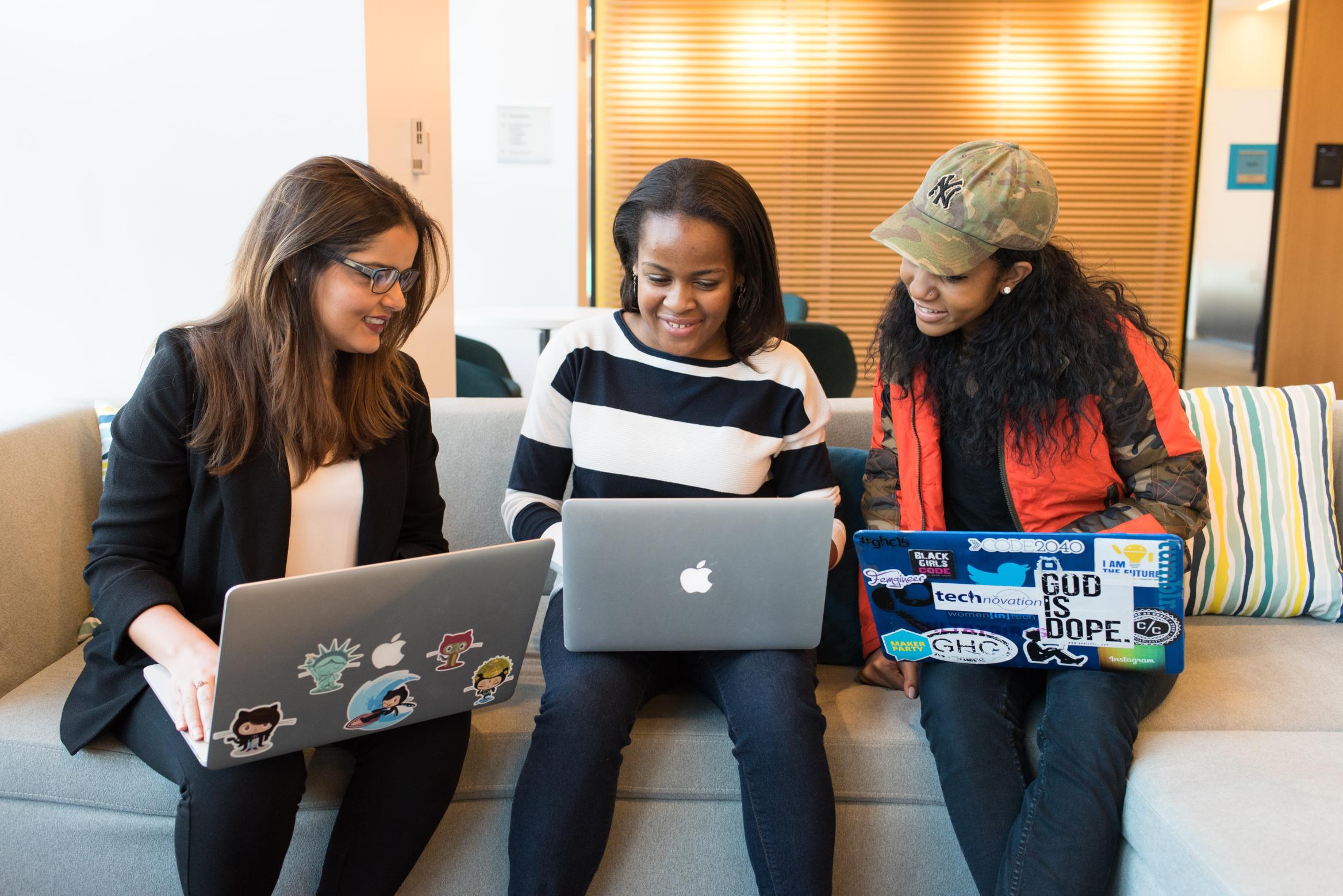 3 junge Frauen mit Laptops tauschen sich aus
