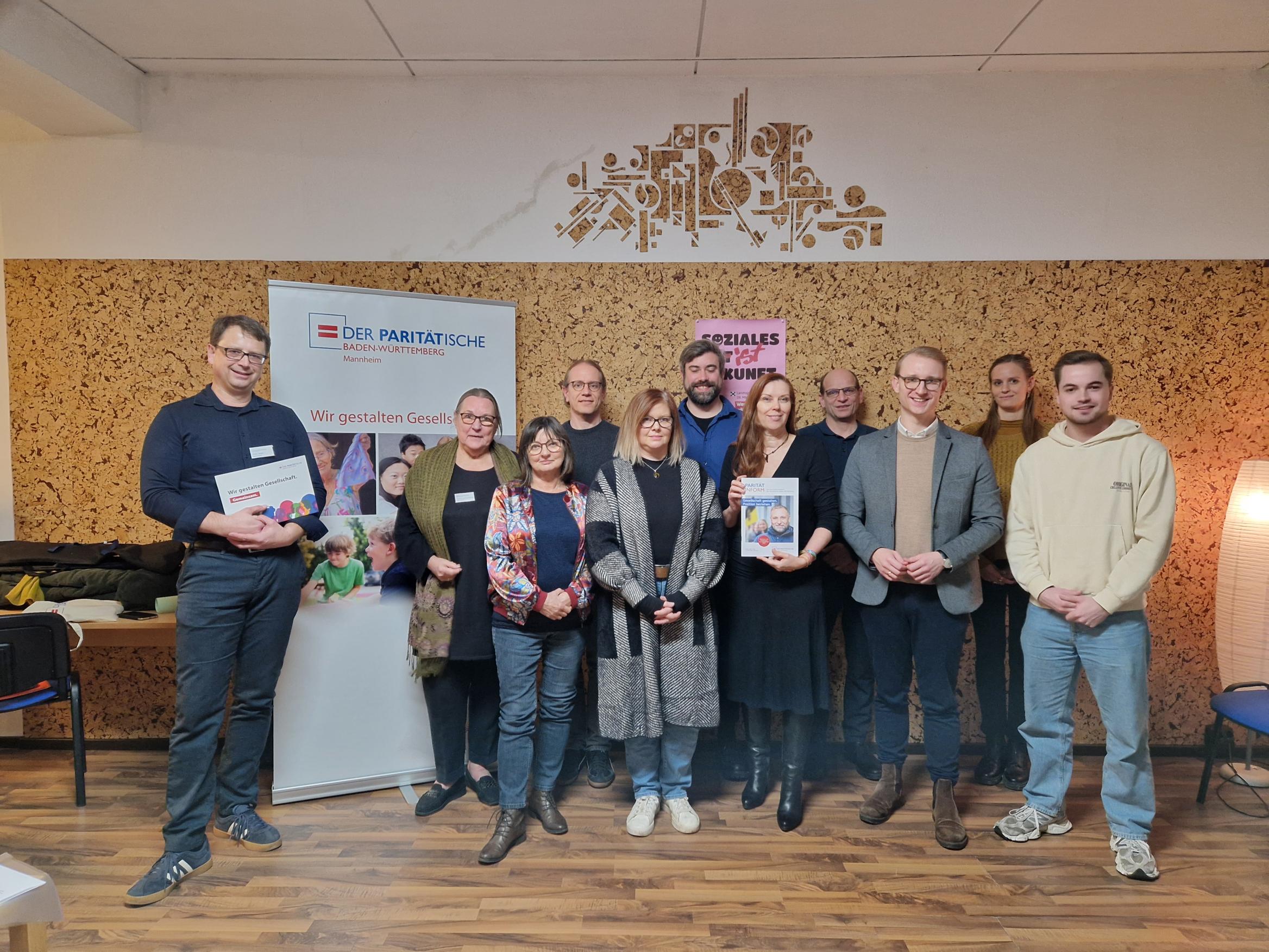 Vor dem Logo des Paritätischen posieren die Teilnehmenden der Veranstaltung: Paritätischer Kreisvorstand Mannheim, Vertreter*innen der Mitgliedsorganisationen und die Kandidierenden