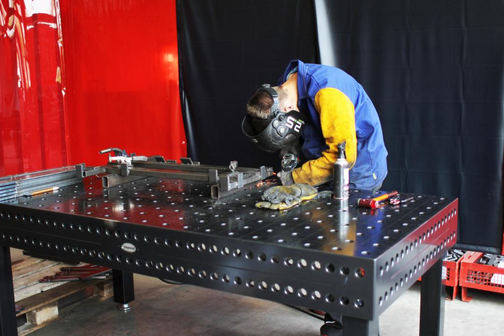 Schweißer in einer Werkstatt an einem Metalltisch