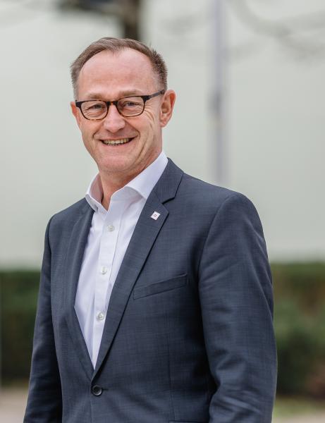 Mann mit Brille in weißem Hemd und blauem Sakko