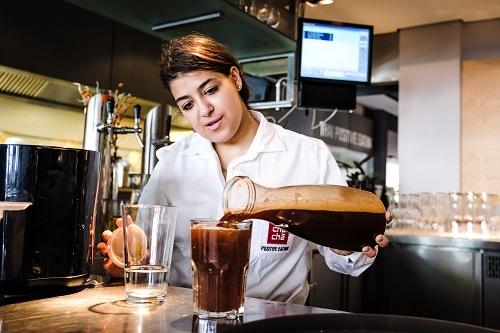 Frau gießt Kaffee in ein Glas