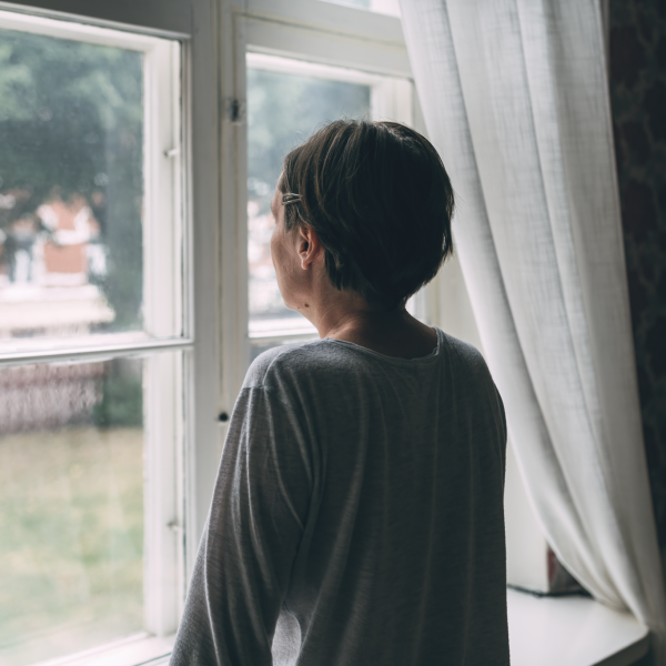 Frau schaut traurig aus dem Fenster