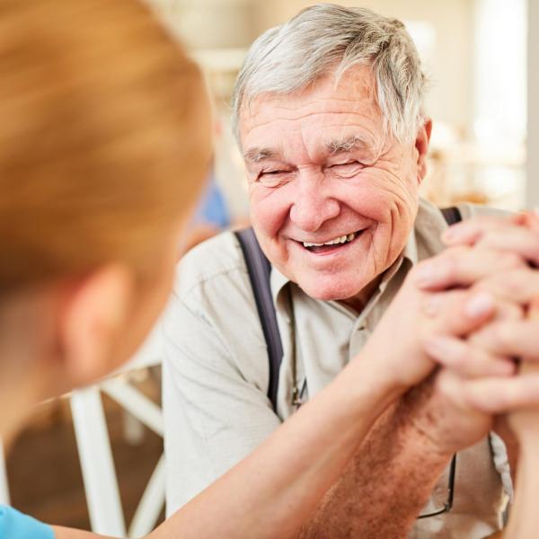 älterer Herr lacht eine Pflegerin an