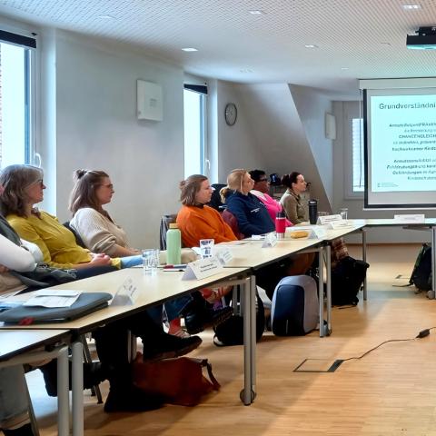 Gruppenansicht vor Leinwand mit Dozentin