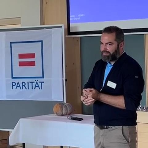 Referent vor Parit&auml;tischem Logo