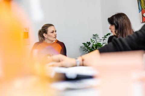 zwei Frauen unterhalten sich an einem großen Tisch