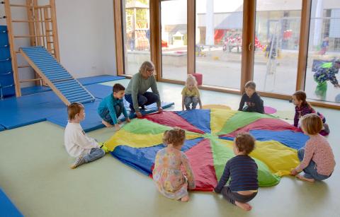 Kinder in einem Bewegungsraum mit einem bunten Tuch
