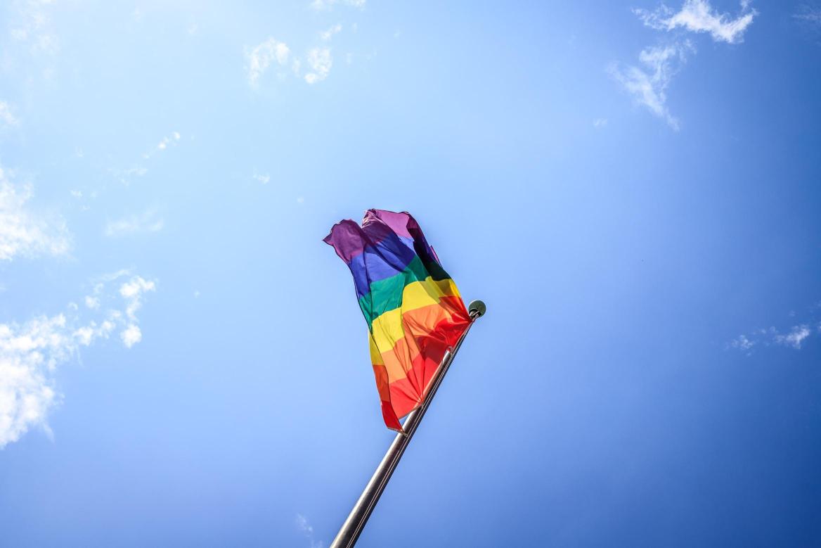 eine Regenbogenflagge vor blauem Himmel