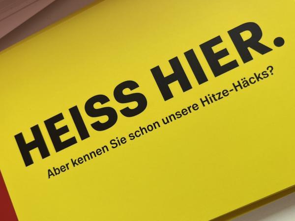 Heiss hier. Auf gelbem Grund. Postkarte
