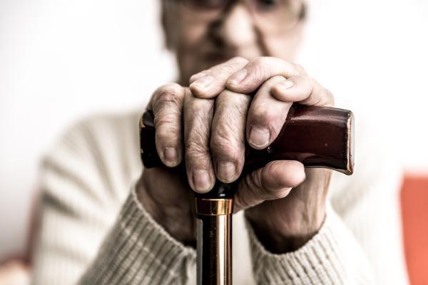 Senior stützt sich auf Gehstock