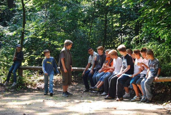 Gruppe Jugendlicher mit einem Erwachsenen im Wald