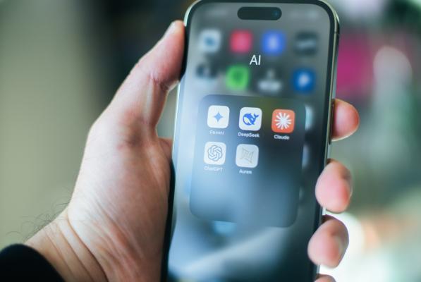 eine Hand hält ein Smartphone mit dem Reiter AI auf dem Screen