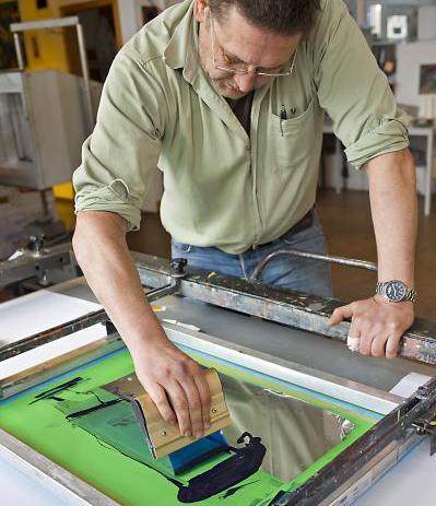 ein Mann streicht Farbe in einer grünen Wanne aus