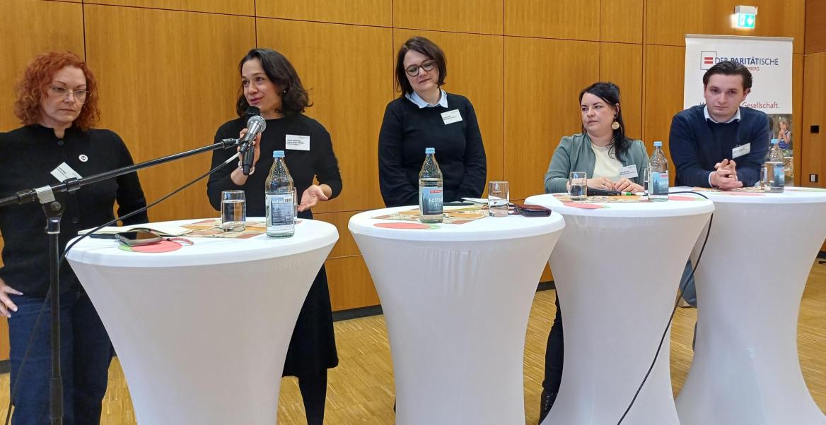 Landtagskandidat*innen stehen an Tischen und sind im Gespräch