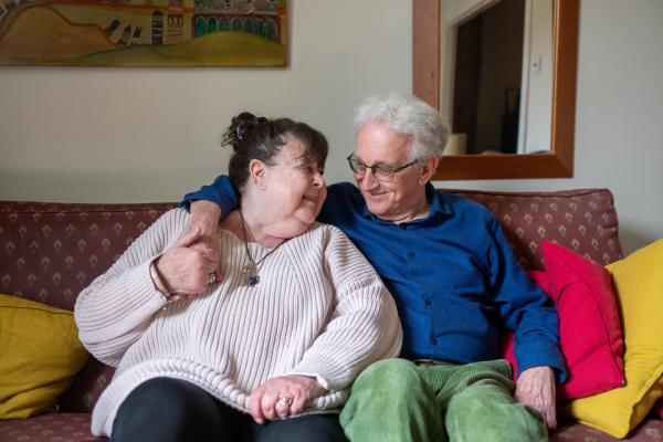 &Auml;ltere und j&uuml;ngere Frau sitzen auf dem Sofa und l&auml;cheln sich an
