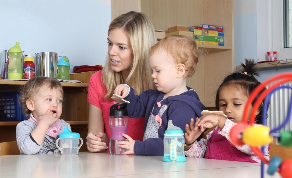 Erzieherin mit kleinen Kindern am Tisch