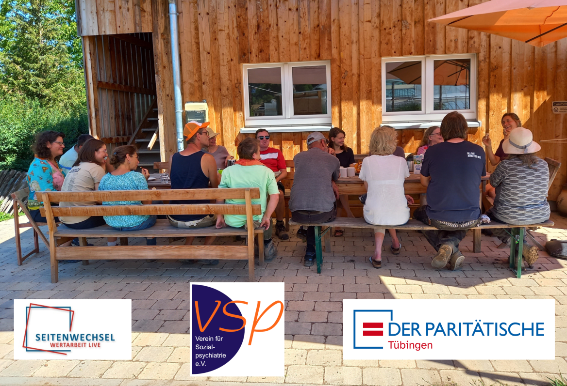 eine Gruppe von Menschen sitzt gemeinsam an einem langen Tisch auf einer Terrasse
