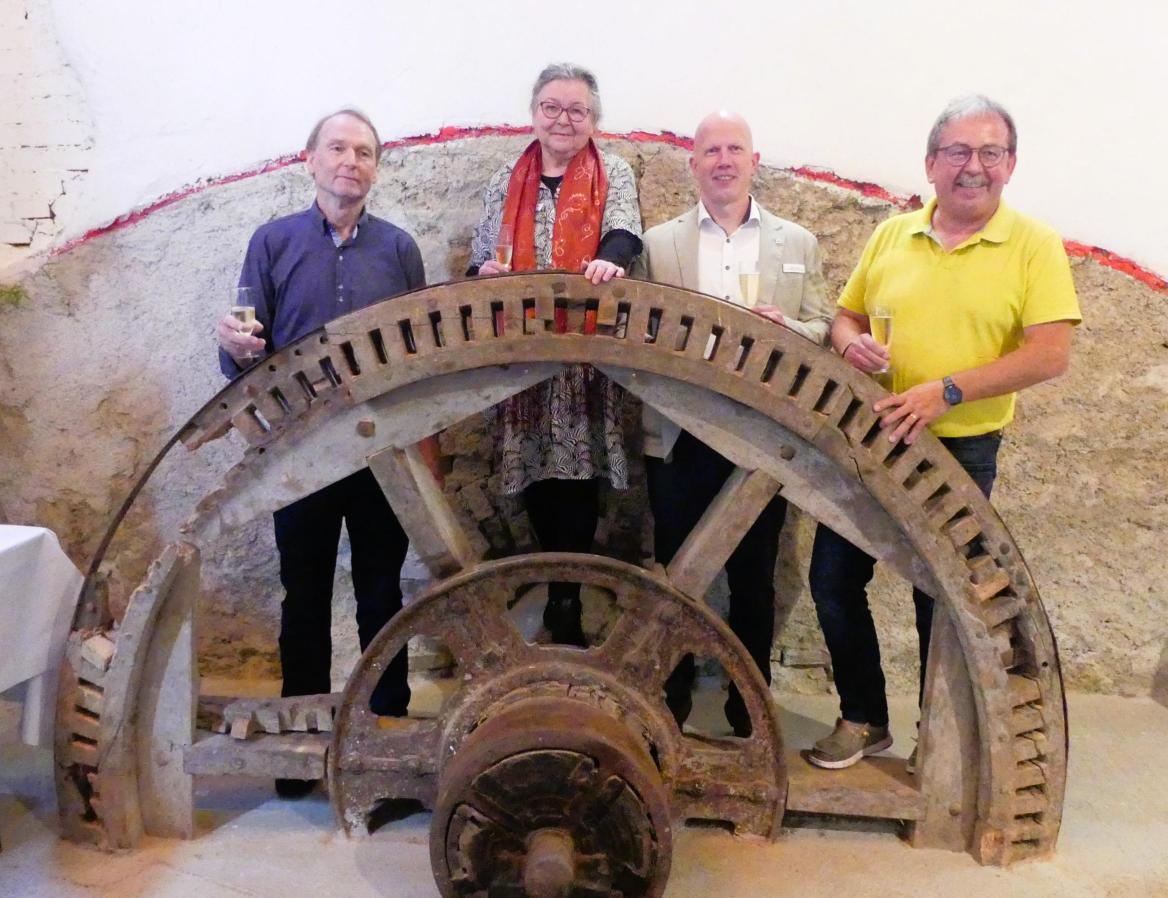 vier Menschen hinter einem alten M&uuml;hlrad