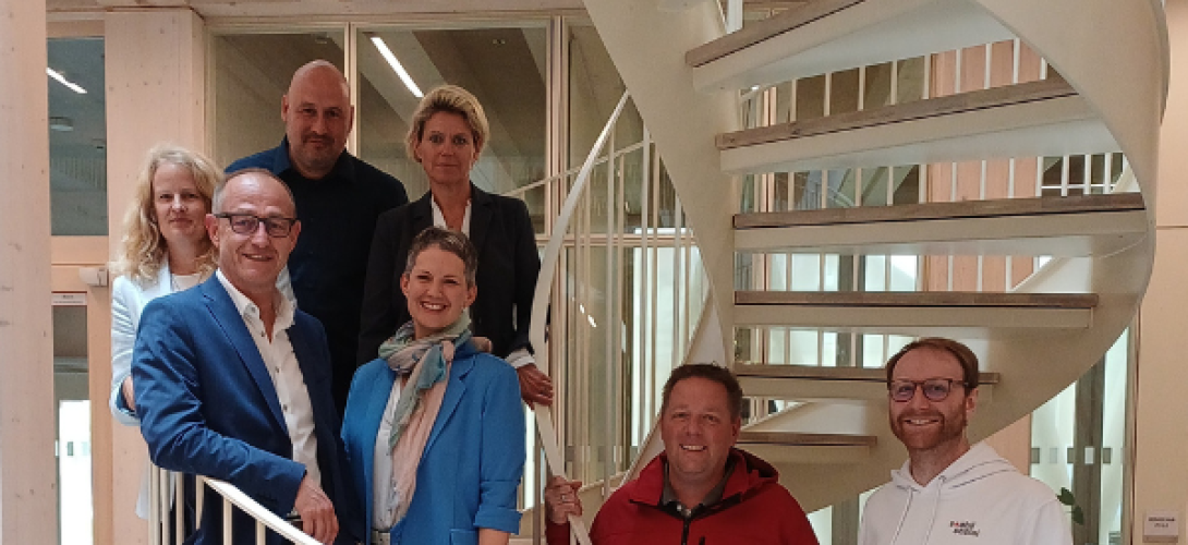 mehrere Menschen stehen auf einer weißen Wendeltreppe