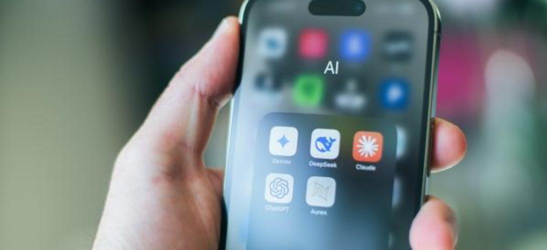eine Hand hält ein Smartphone mit dem Reiter AI auf dem Screen