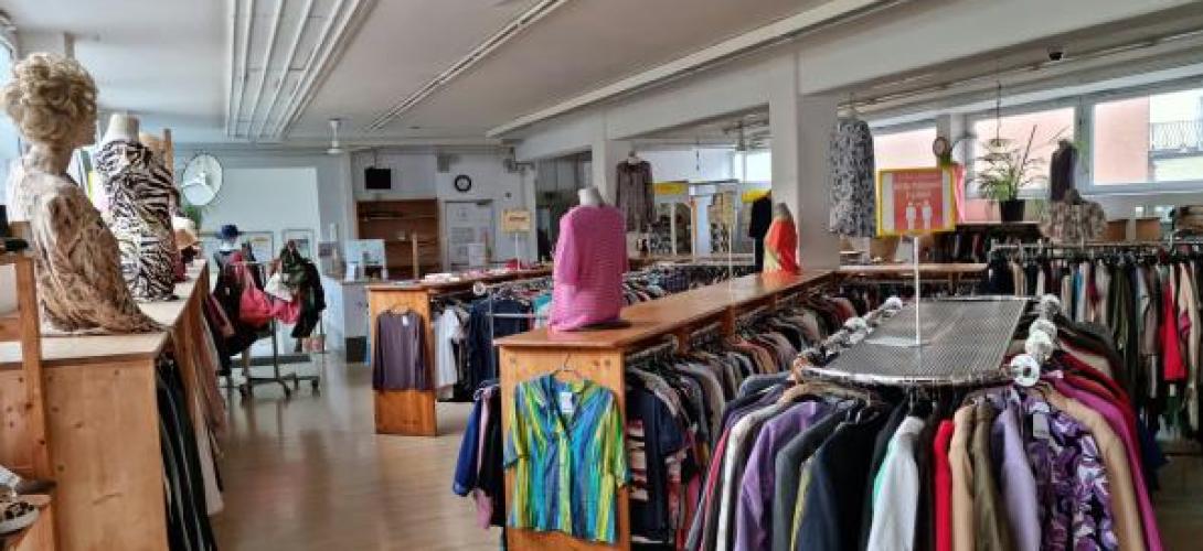 Blick in einen Bekleidungsgeschäft, mit Ständern mit Kleidern.