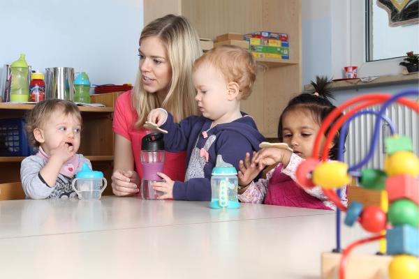 Junge Frau mit Kindern in der KiTa
