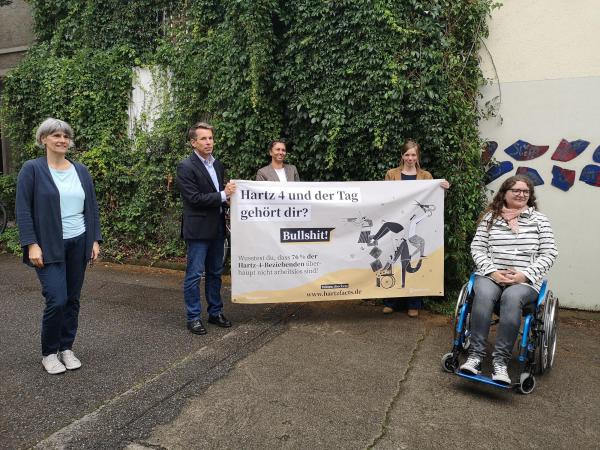 Die fünf Sprecher präsentieren das Plakat: "Hartz 4 und der Tag gehört Dir? Bullshit!"