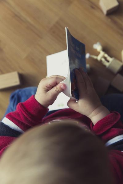 Kind von Hinten blättert in Buch