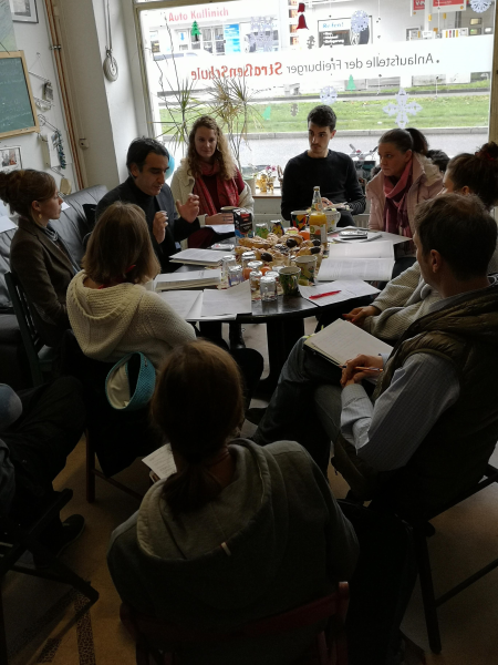 Am Tisch sitzen mehrere Personen im Gespräch