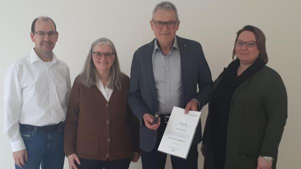 2 Frauen und 2 Männer, davon einer mit einer Urkunde und einer Ehrennadel