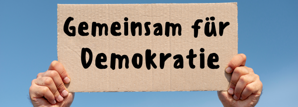 Schild mit gemeinsam für Demokratie wird mit zwei Händen hochgehalten