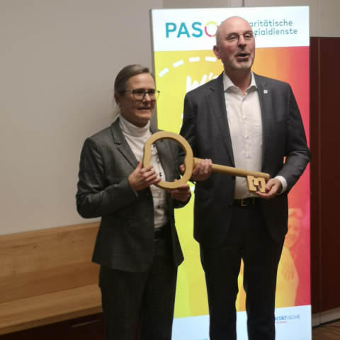 zwei Menschen halten einen großen Schlüssel