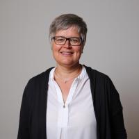 lächelnde Frau mit kurzen Haaren und Brille
