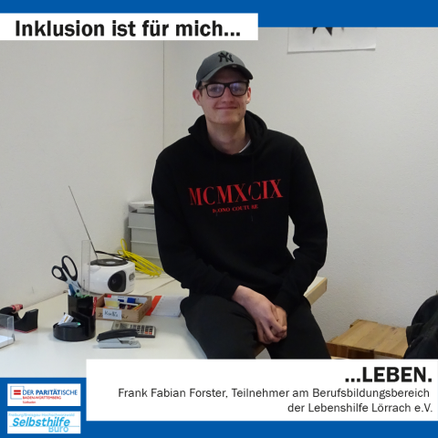 Ein junger Mann sitzt lächelnd auf dem Schreibtisch. Darunter steht: "Inklusion ist für mich LEBEN. Frank Fabian Forster, Teilnehmer am Berufsbildungsbereich der Lebenshilfe Lörrach e. V."