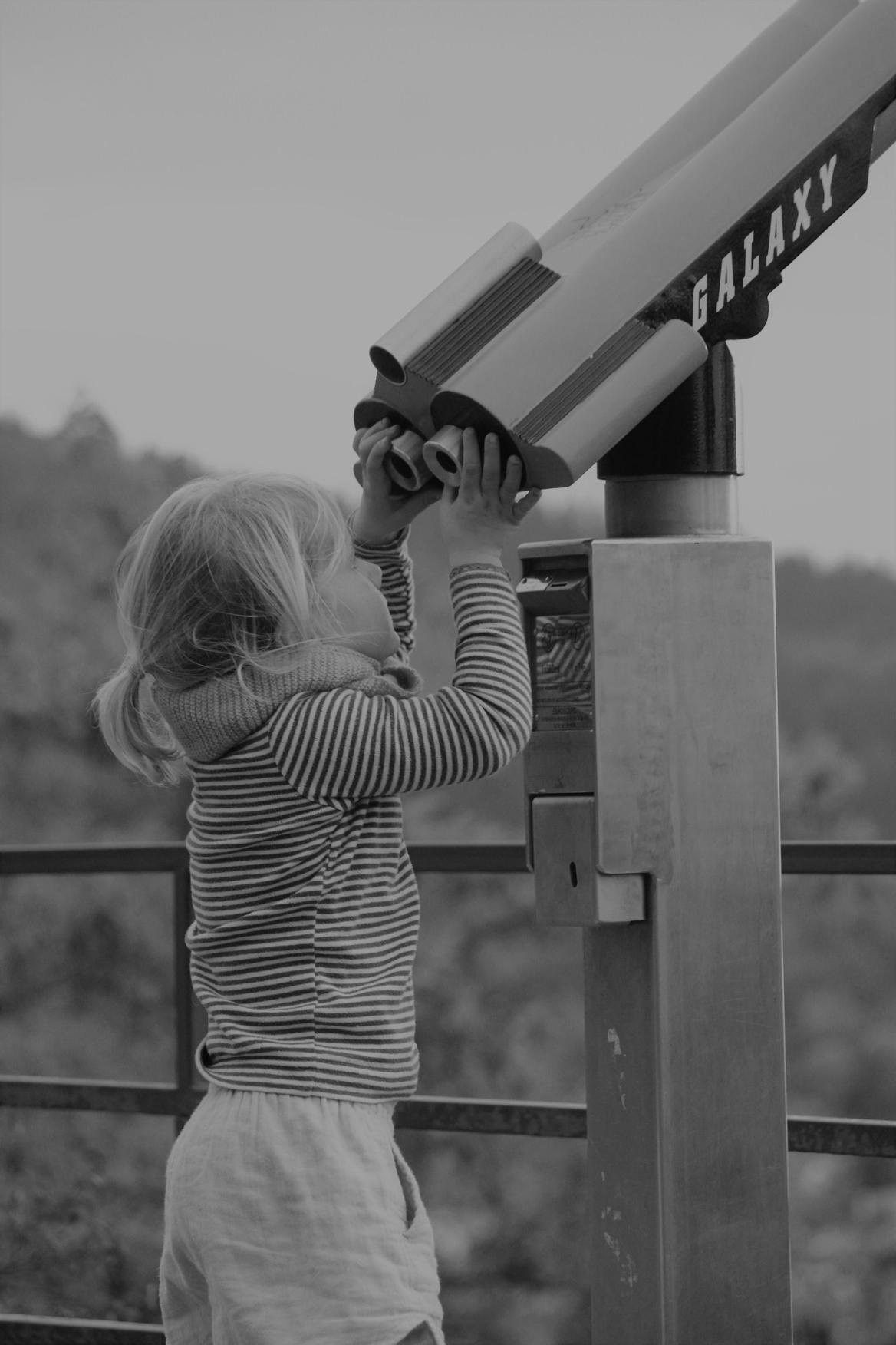 Das Bild zeigt ein Mädchen an einem großen Fernrohr.