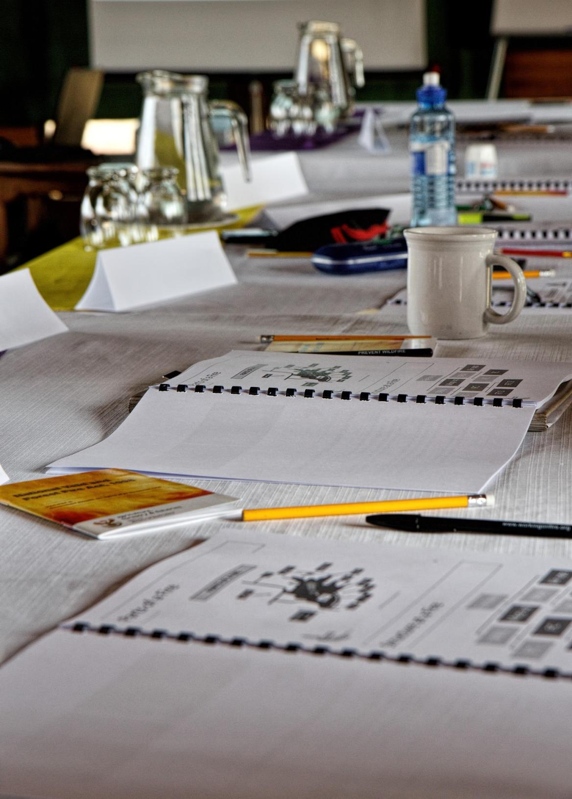 Das Bild zeigt einen Tisch mit Unterlagen und Getränken.