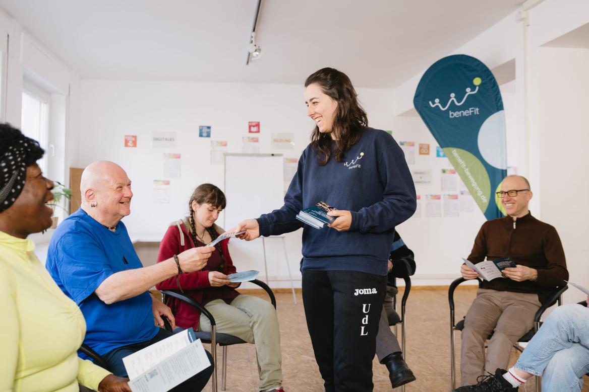 Mitarbeiterin von beneFit e.V. verteilt Flyer des Vereins