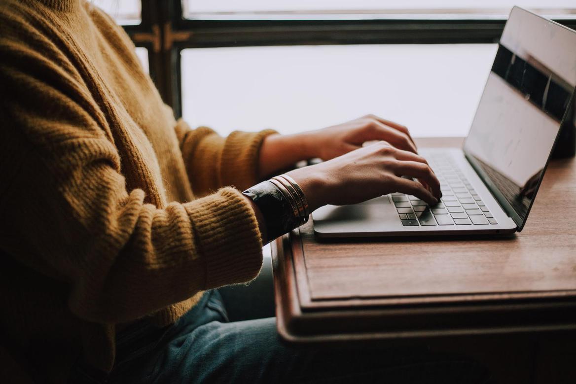 Eine Person sitzt und arbeitet an einem Laptop