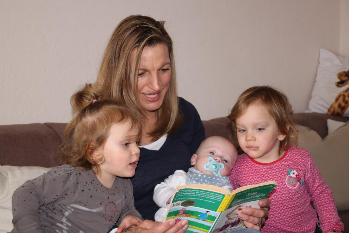 Familienpflegerin beim Vorlesen mit 3 Kindern