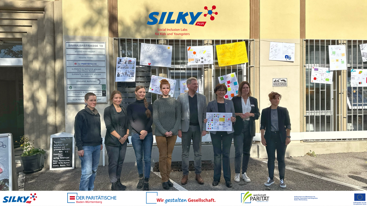 M&auml;nner und Frauen stehen vor Kinderplakaten