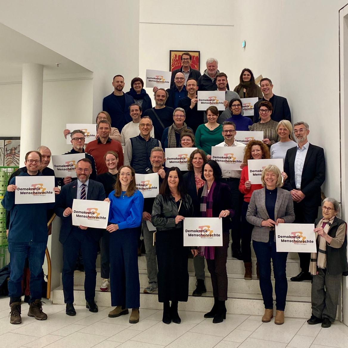 M&auml;nner und Frauen auf einer Treppe, die Schilder "Demokratie und Menschenrechte" hochhalten