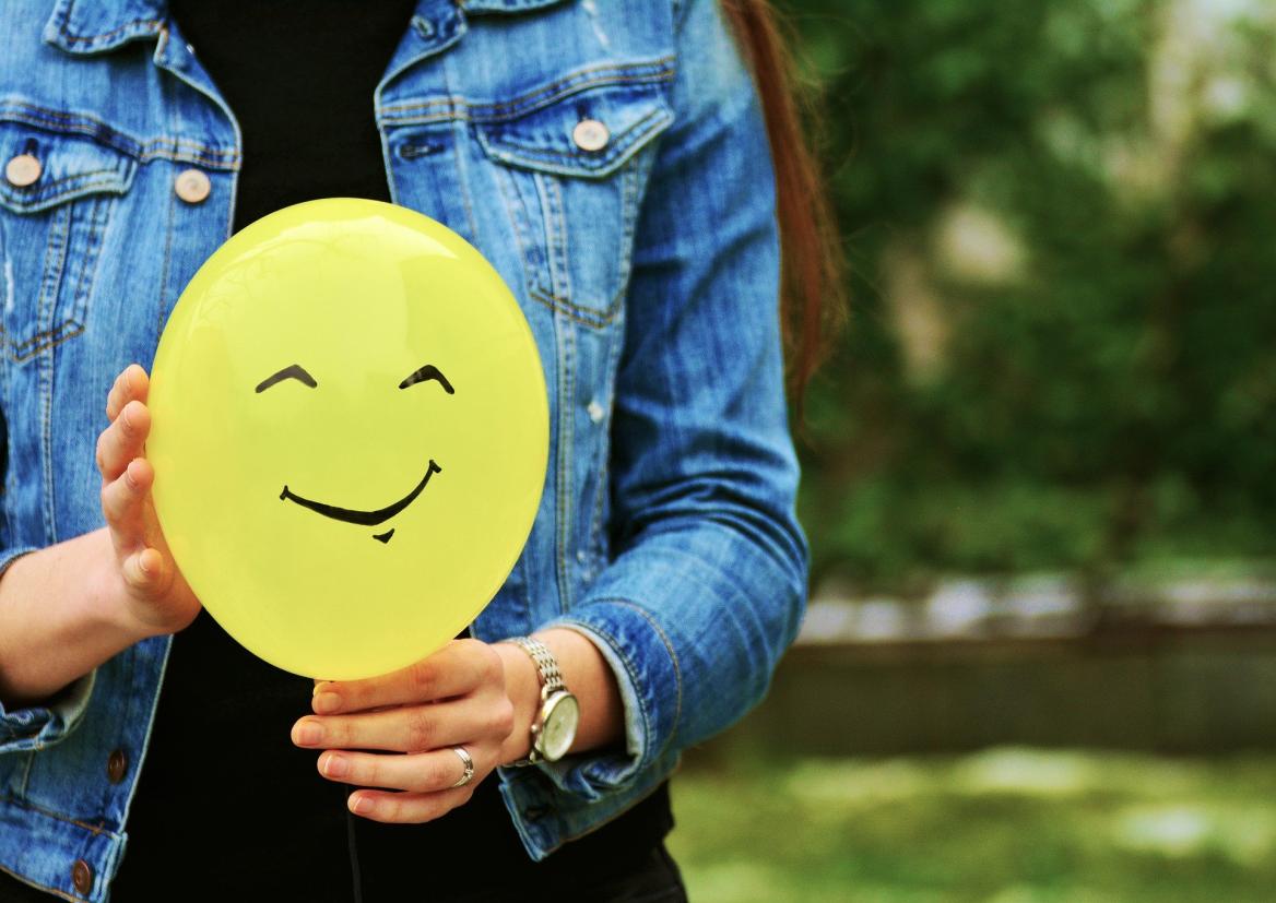 Jubger Mensch h&auml;lt gelben Smily in der Hand