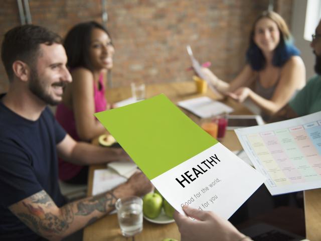 M&auml;nner und Frauen sitzen freudig am Tisch