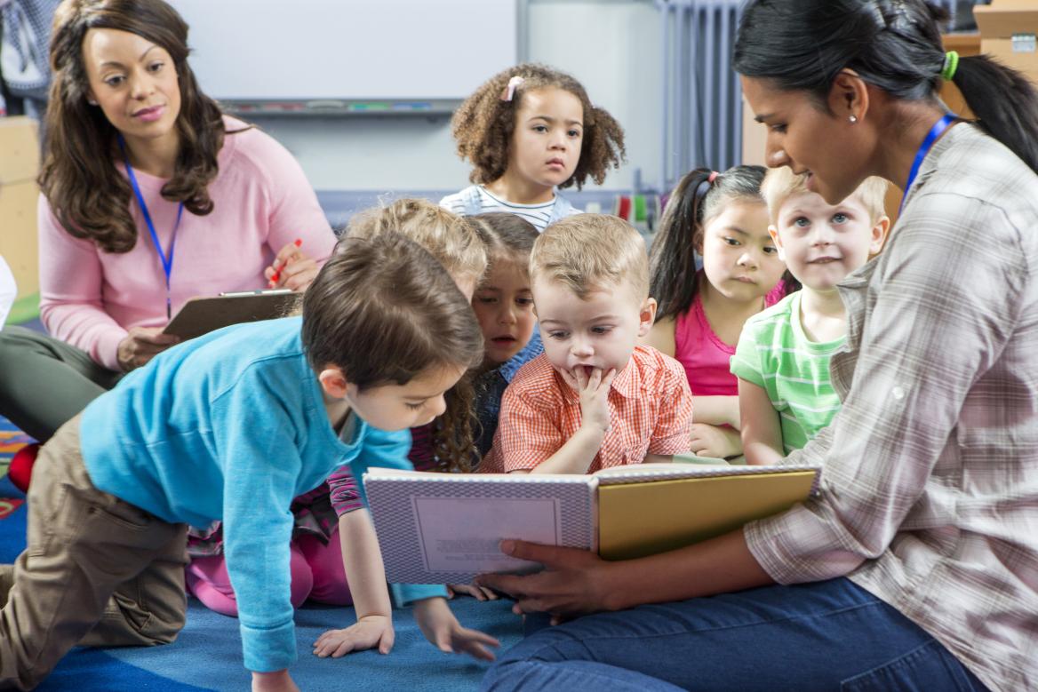 Kinder schauen mit Erwachsenen in ein Buch