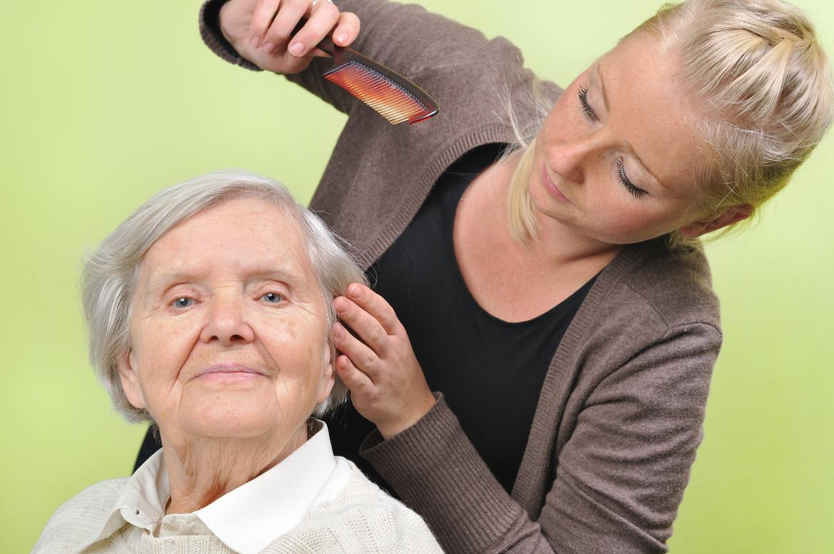 Junge Frau k&auml;mmt &auml;lteren das Haar