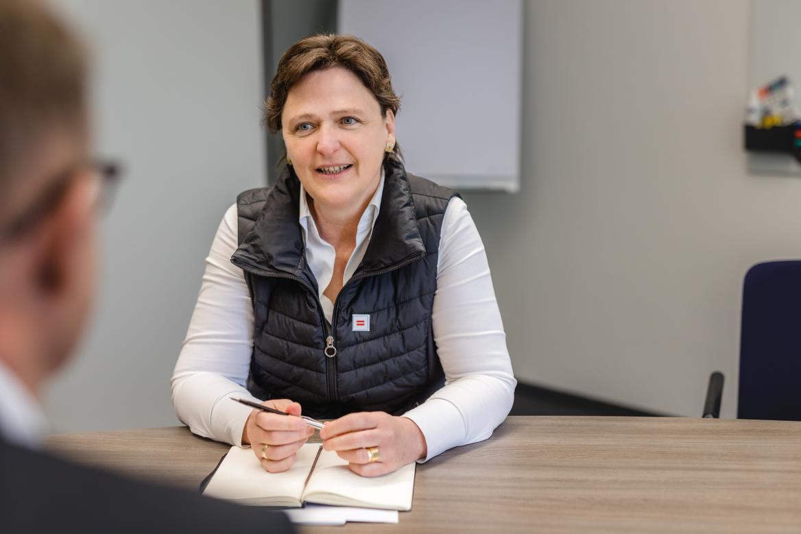 Frau sitzt an Tisch mit Stift in der Hand