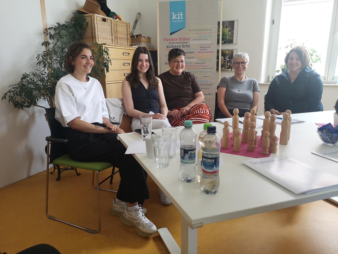 f&uuml;nf Frauen sitzen an einem wei&szlig;en Tisch