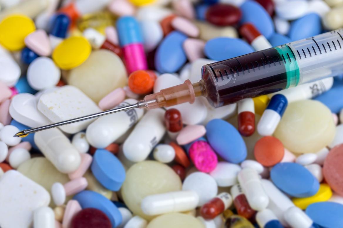 viele bunte Tabletten und eine Kan&uuml;le, die offensichtlich eine illegale Substanz enth&auml;lt