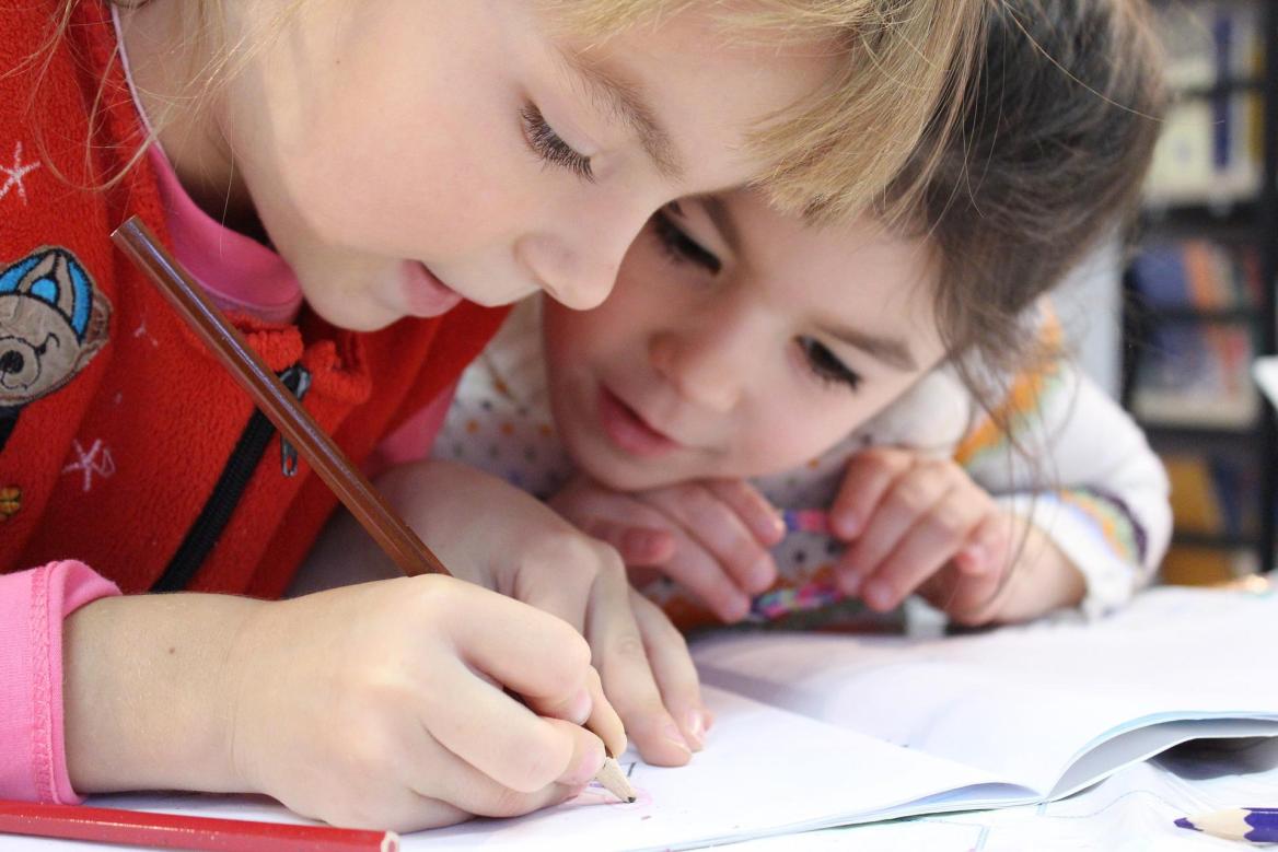 Zwei Kinder &uuml;ber Schulheft gebeugt